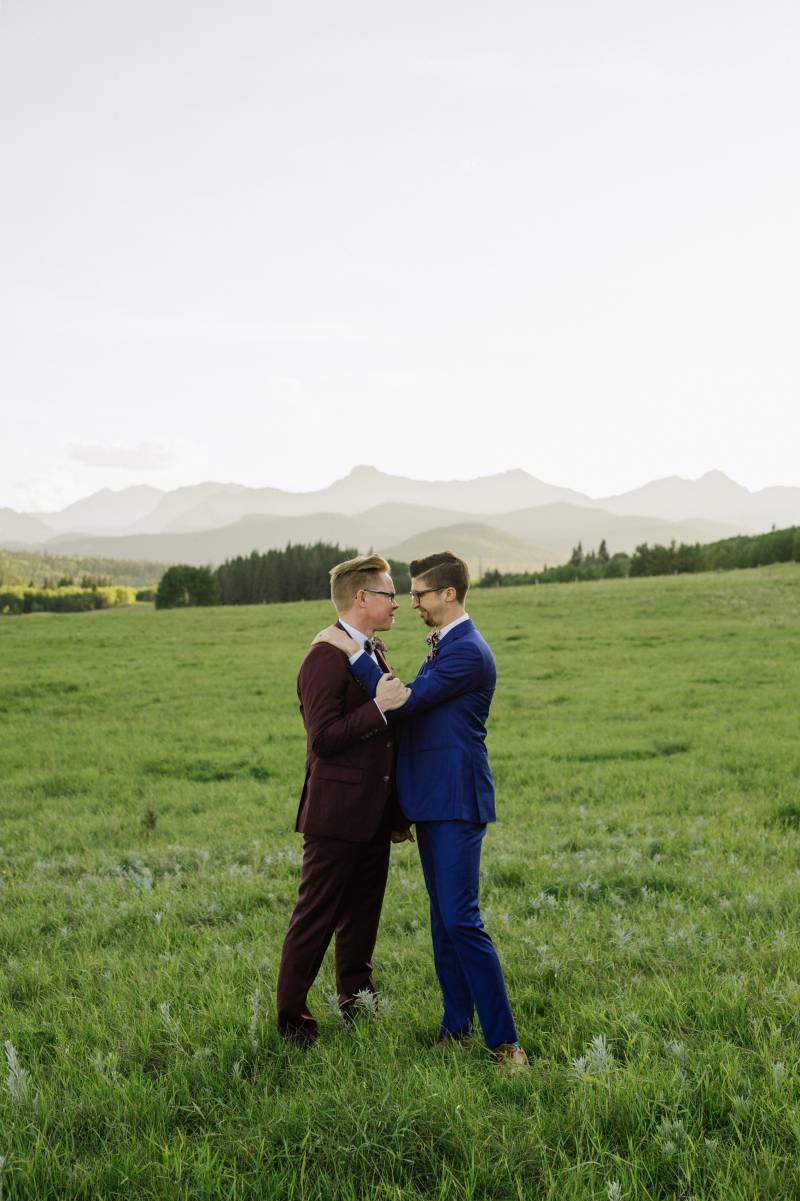 Grooms standing smiling in large open grassy field