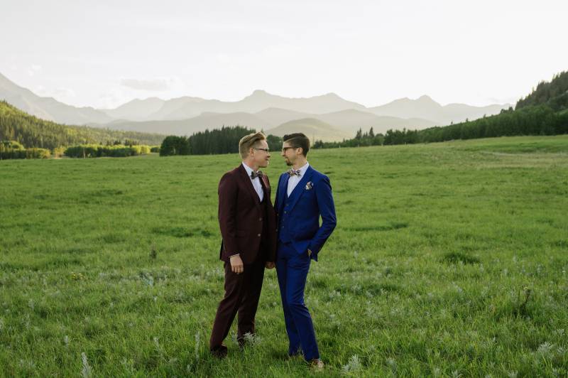 Grooms standing smiling in large open grassy field