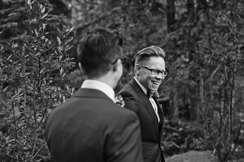 Grooms smiling in forested area black and white 