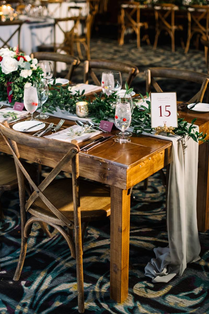 Wood table and place settings with rustic chairs and draping grey fabric table runner