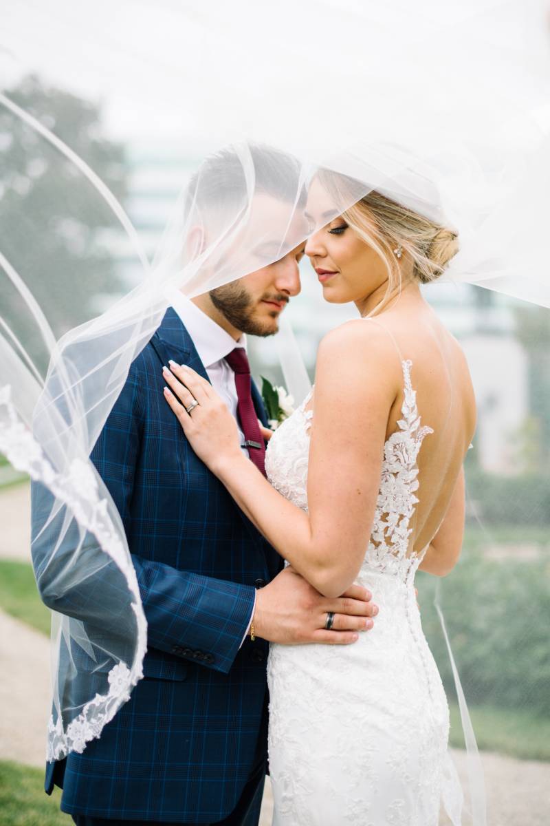 Bride and groom embrace as white veil falls overhead