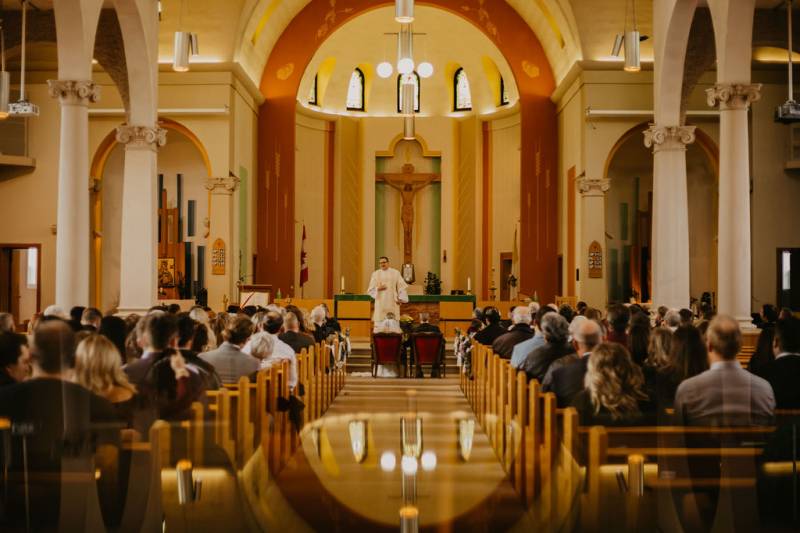 Church seating filled with guests and officiant standing facing pews