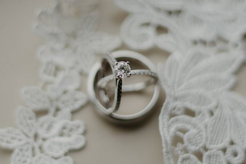 Wedding ring flat lay beside white embroidered fabric