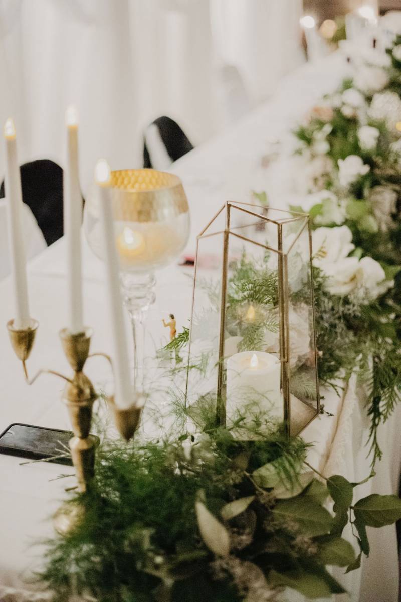 Gold candelabra and green and white table runner next to white gold goblet 