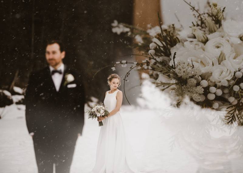 Superimposed white flower bouquet over bride in white dress and groom in black suit