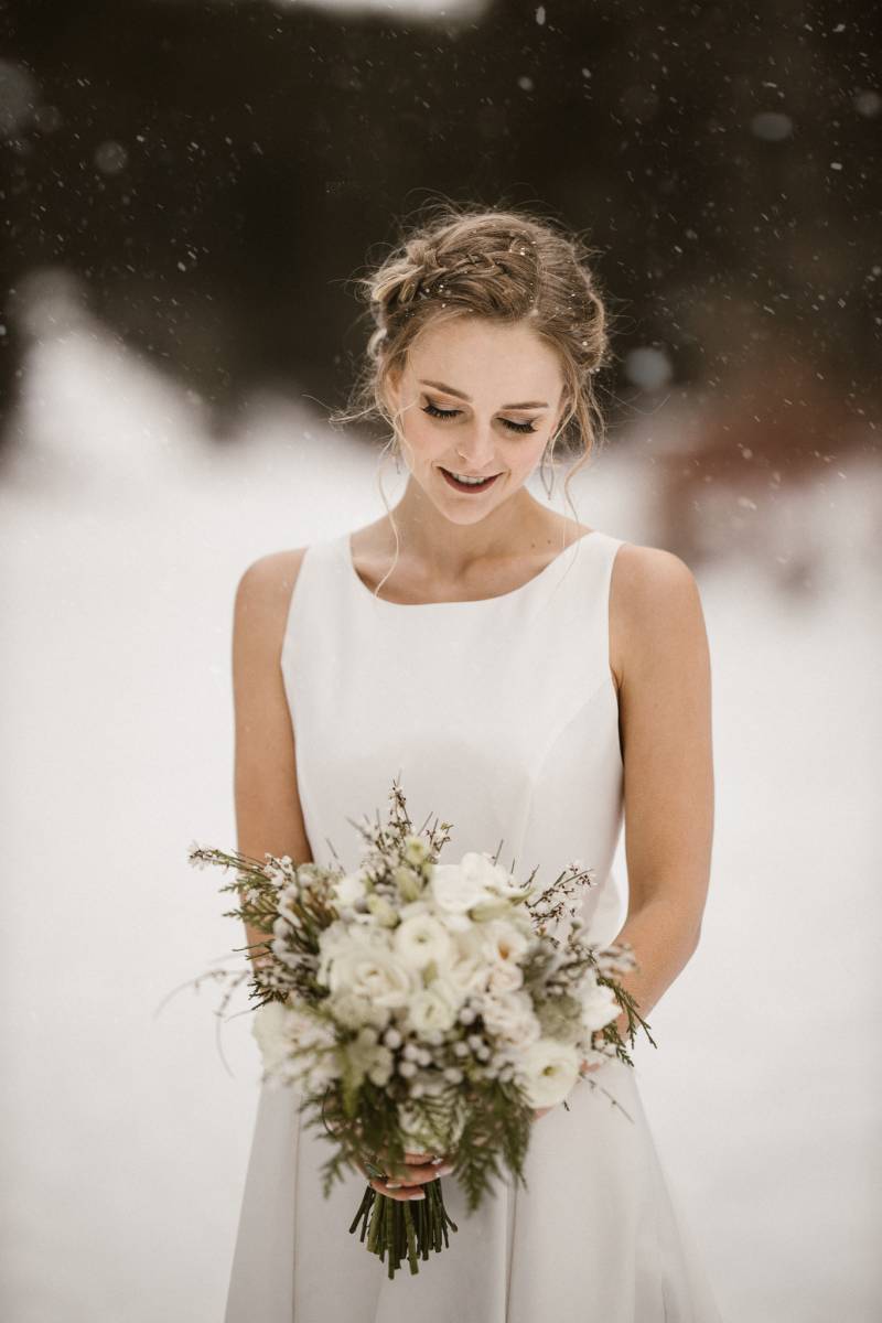 Bride in white dress smiling holding white bouquet 