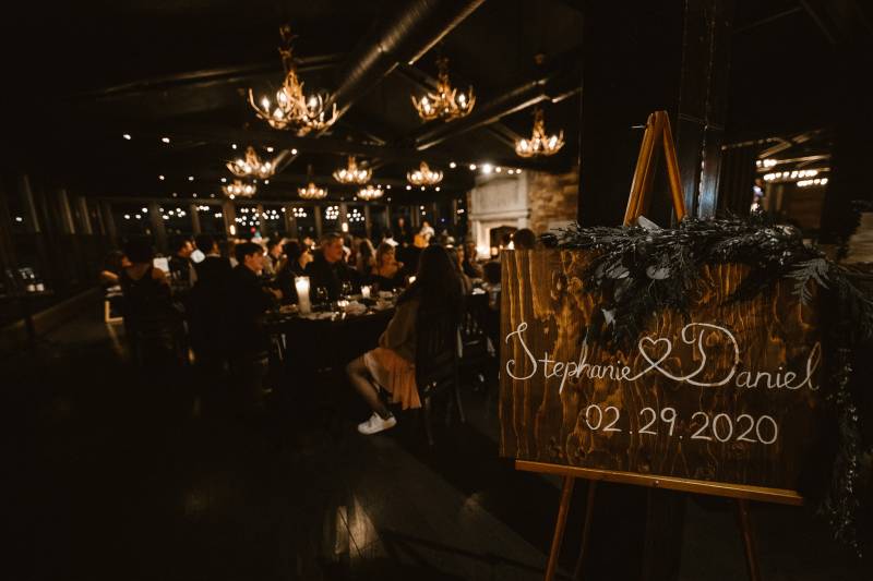 Wooden wedding sign on wood aisle under candle lit and antler chandelier 