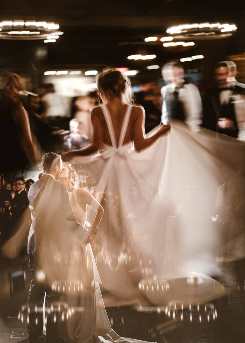 Bride and groom kissing overtop bride spinning large white dress blurred 