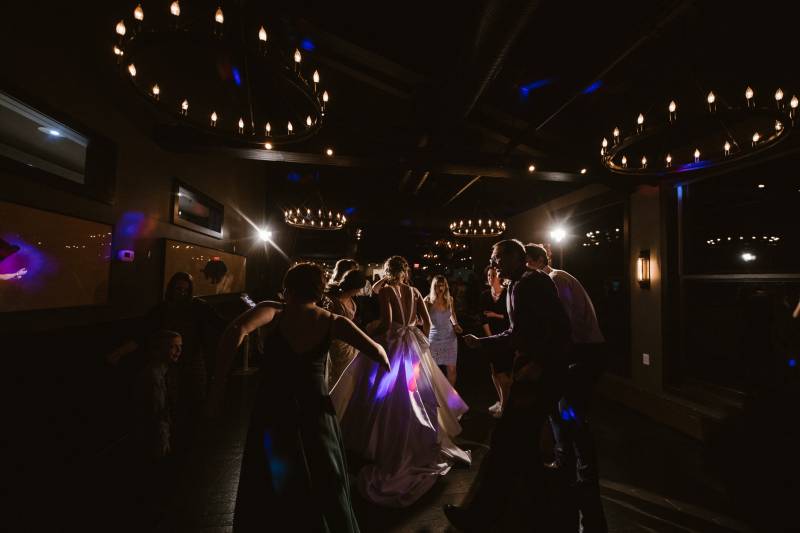 Guests dance and laughing under dimly lit chandelier lights 
