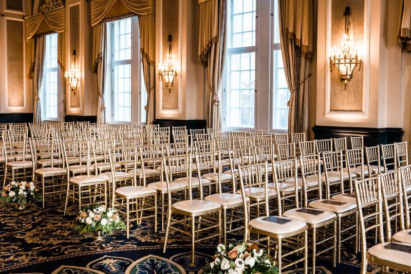 Rows of gold legged chairs and bronze and white bouquets 
