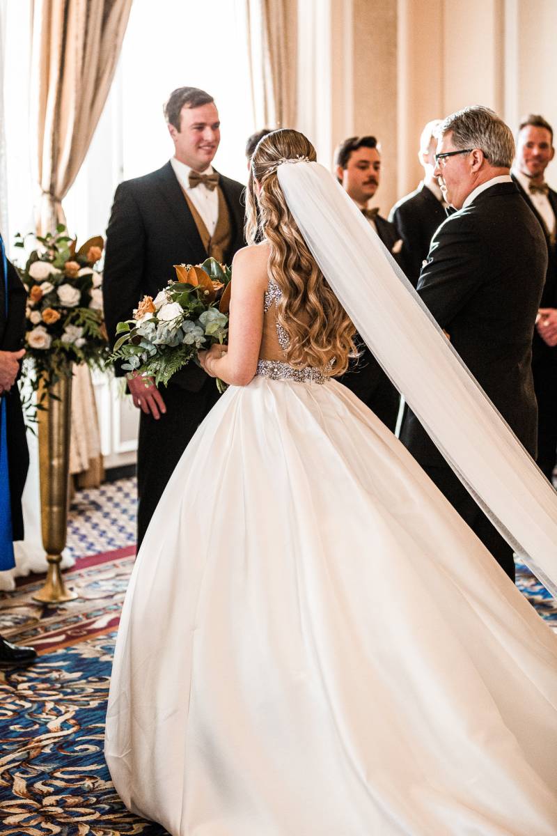 Bride with lack embroidered open back bodice and long white veil holding bouquet