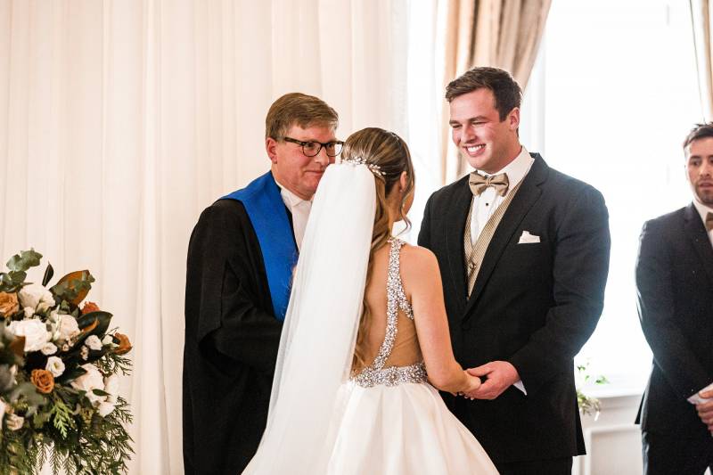 Bride and groom face one another in front of officiant 