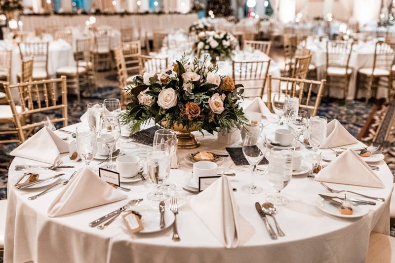 Wedding reception table place settings with golden vase bouquet centrepiece  