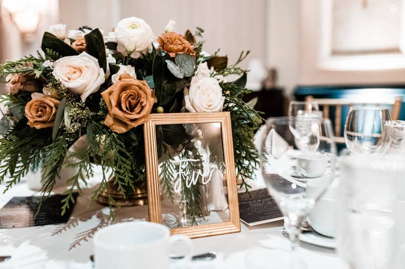 Wedding reception place setting with white and bronze floral centrepiece 