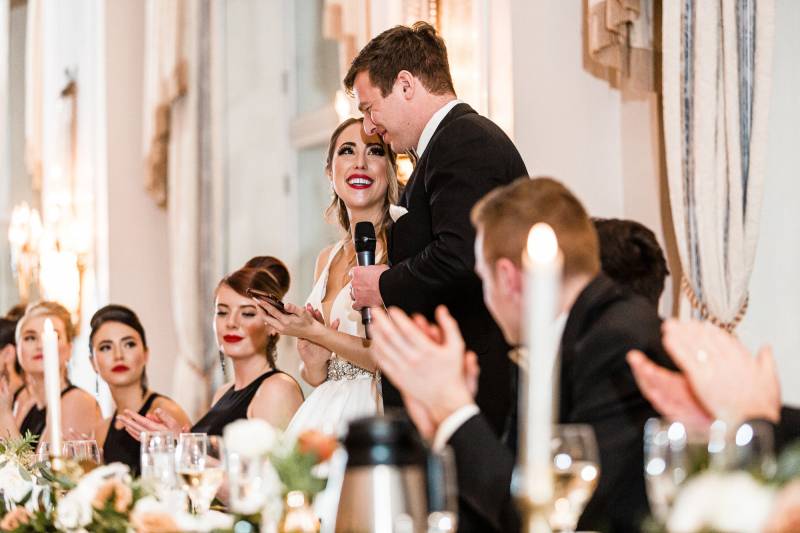 Bride and groom standing at head table holding microphone
