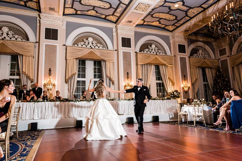 Bride dancing with father in large candlelit room on large open wood floor
