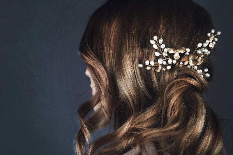 Back of head of woman with curly brown hair and white floral hairclip 