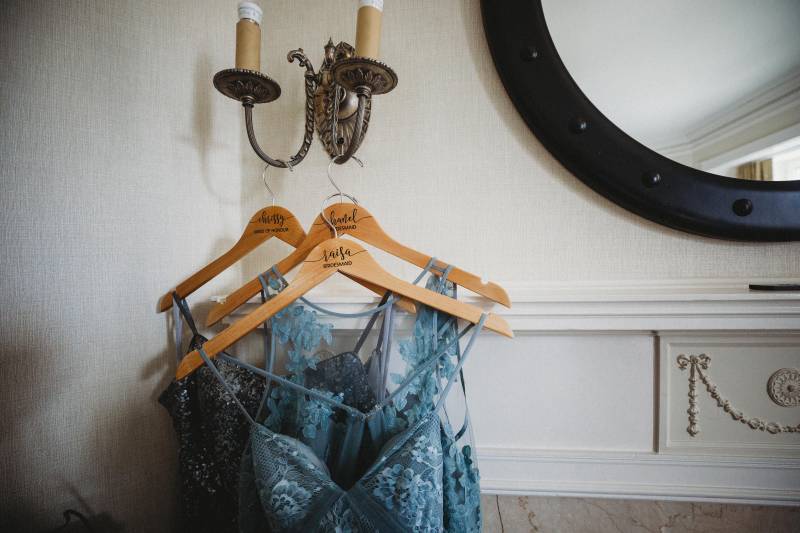 Three blue wedding dresses hanging from candelabra from wall beside mirror  
