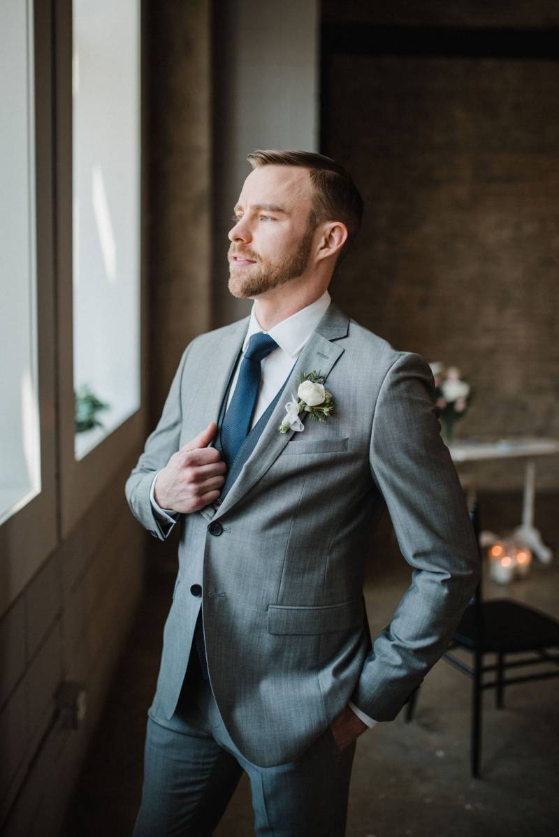 Man in blue grey suit and navy tie staring out a window 