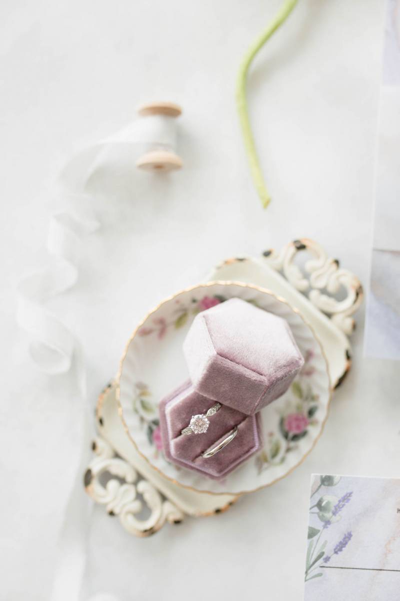 Lavender ring box on white table on top of tea plate 