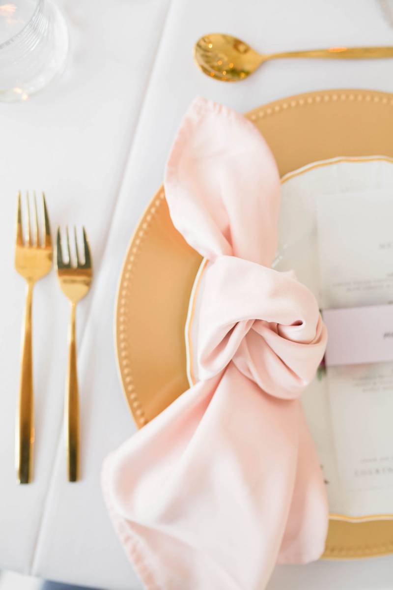 Table setting flat lay with gold cutlery and blush napkin