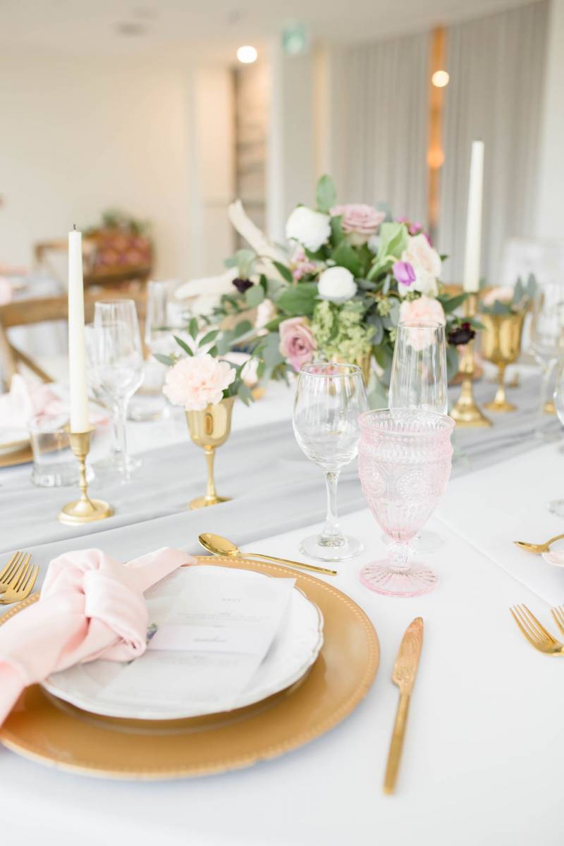 Table setting with gold accents and candle sticks and floral centerpiece 