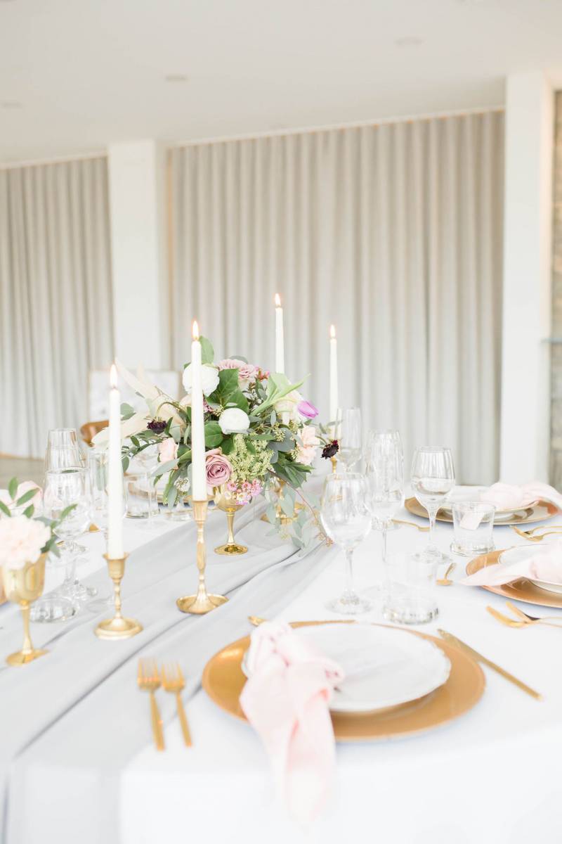 Table setting with gold accents and candle sticks and floral centerpiece 