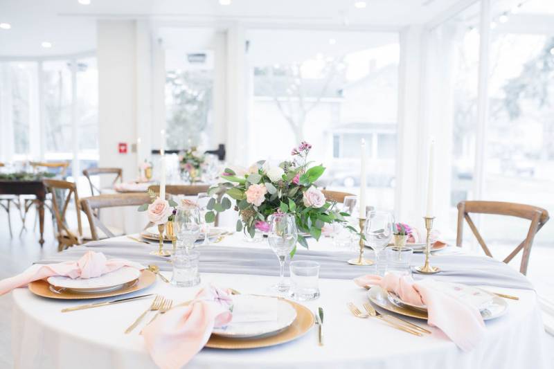 Table setting with gold accents and candle sticks and floral centerpiece 