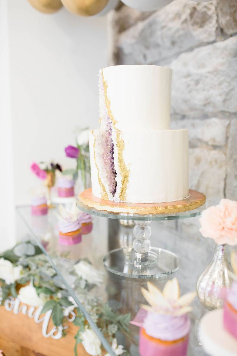 White wedding cake with purple and gold rock candy slice on glass table 