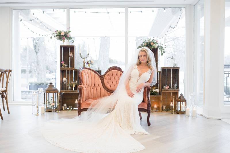 Bride leaning on salmon antique chair in large white dress and veil 