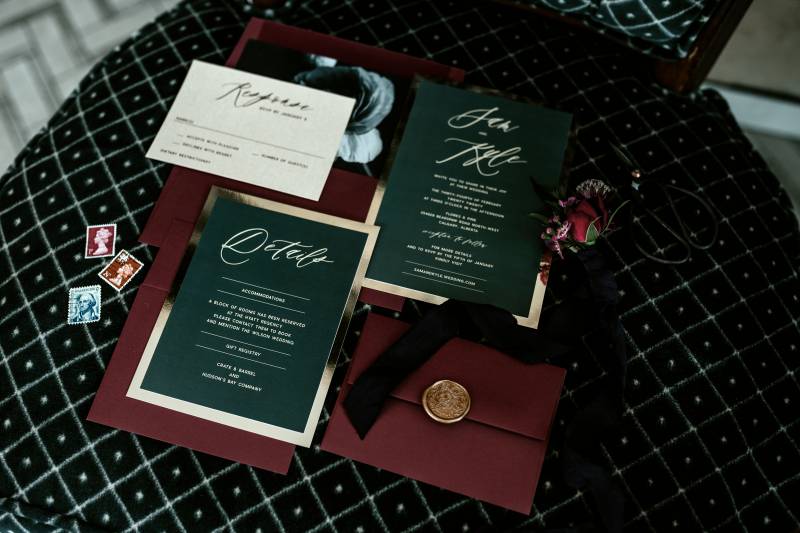 Black burgundy and gold wedding invitation flat lay on black table 