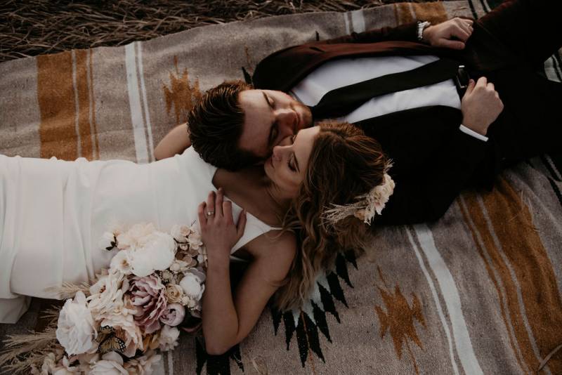 Bride and groom lay opposite on brown and orange tapestry