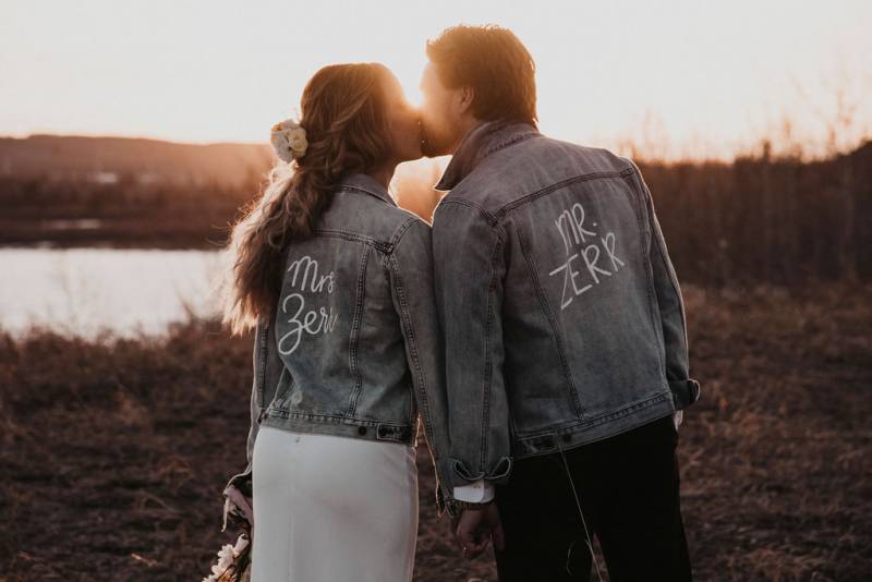 Bride and groom kiss wearing mr and mrs jean jackets 