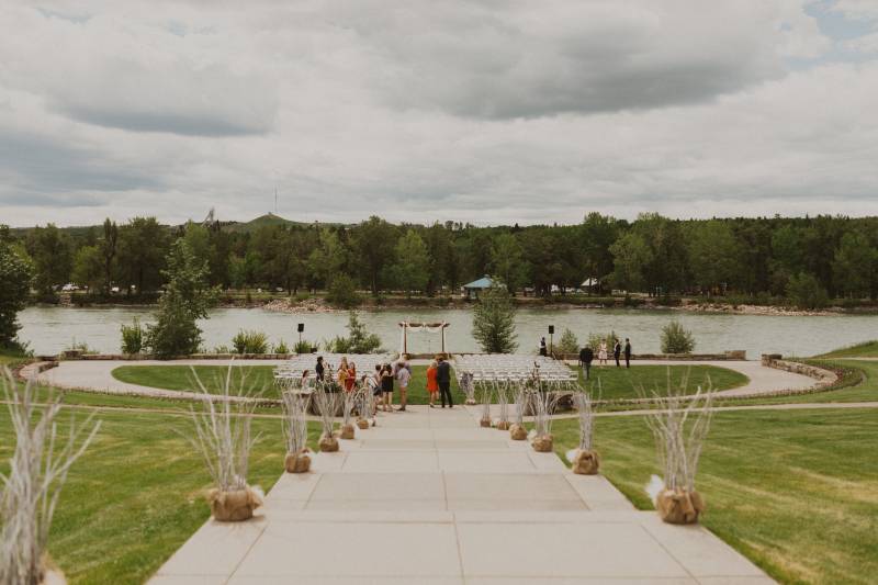 Concrete stairs leading to grassy open field with wedding arch and chairs in front of river