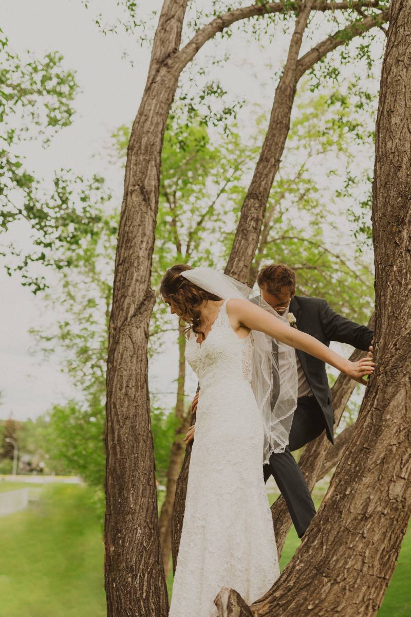 Bride and groom hold onto tree climbing up