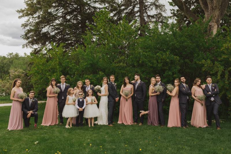 Bridesmaids and groomsmen stand in pairs to the side of bride and groom standing back to back 