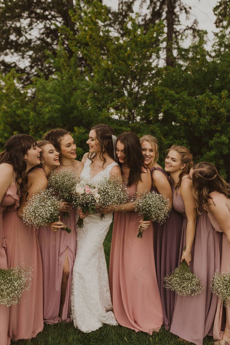 Bride stands smiling in between bridesmaids holding white bouquets smiling
