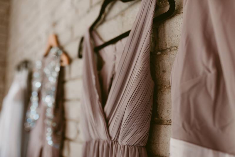 Four pastel dresses hanging in row on brown brick wall