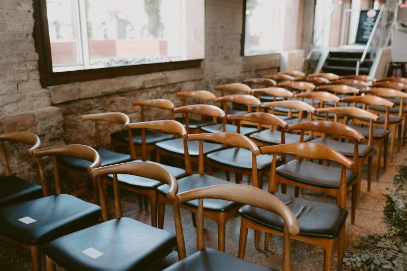 Light brown chairs with black cushions in brick room with natural light 