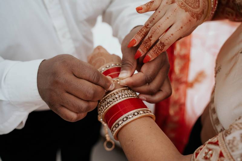 Man helps put bracelet on woman with henna 