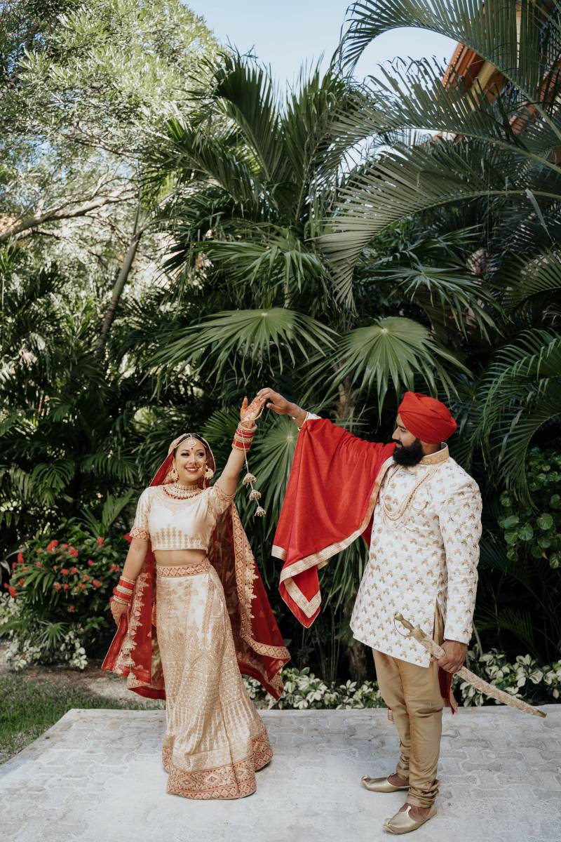 Man wearing traditionally wedding attire holding sword spins bride on outstretched arm