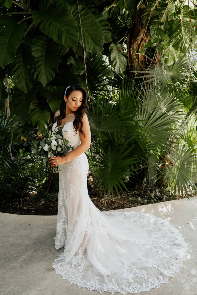 Bride looks over shoulder in white lace dress holding white bouquet 