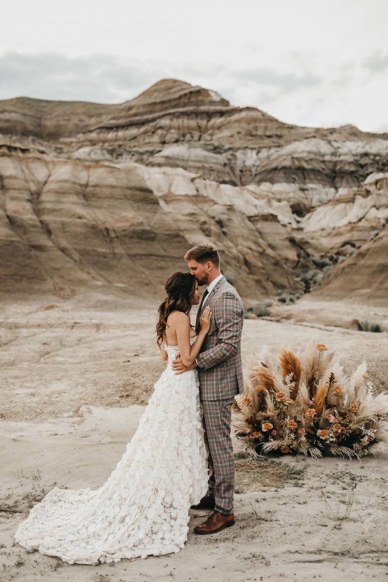 Mand and woman embrace kissing forehead with desert background