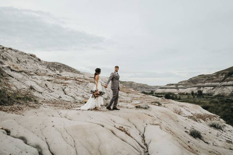 Man and woman walk together on rolling dirt hills holding hands 