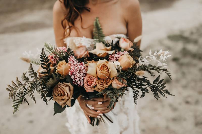 Holding out bouquet with beige pale pink and white flowers