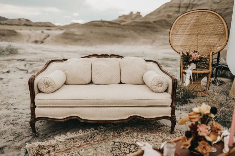 Large beige couch sitting beside wicker seat on top of rug