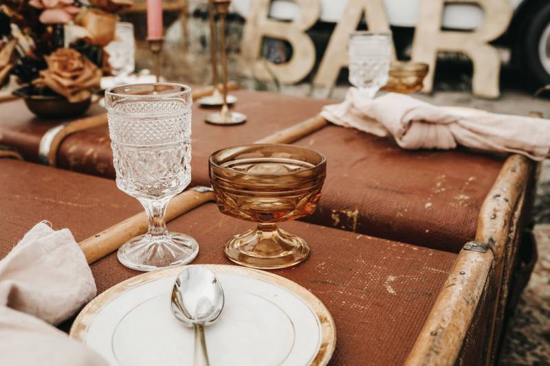 Table setting on top of brown luggage with two chalices and silver cutlery
