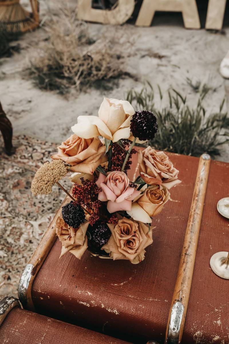 Pale pink white and beige floral arrangement on old luggage box 