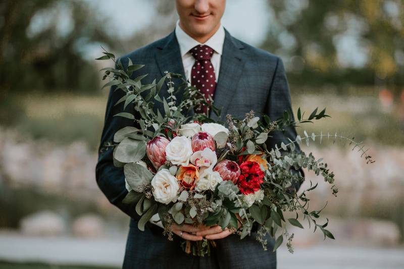 Groom holding pink red and white bouquet 
