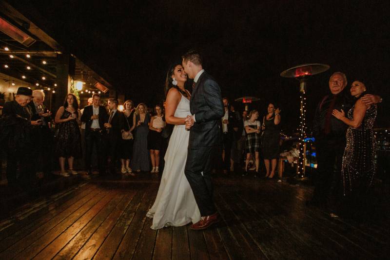 Bride and groom dancing on wooden boardwalk at night 